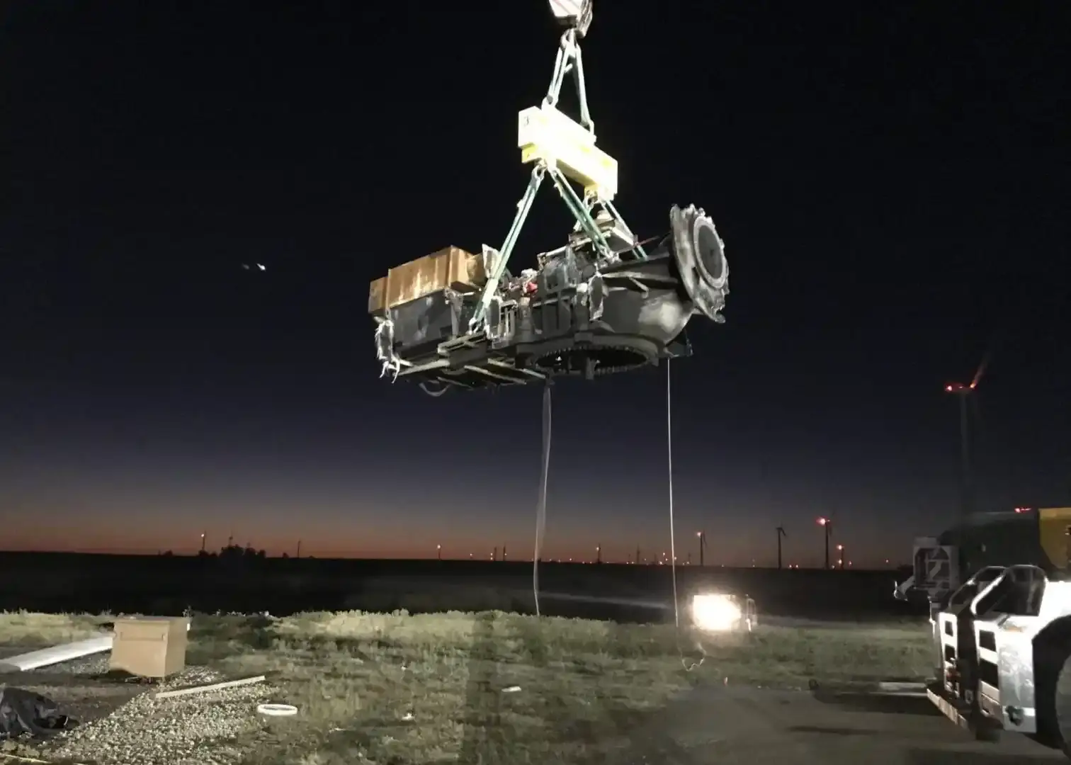 Aegis crew lifting a wind turbine nacelle component at dusk